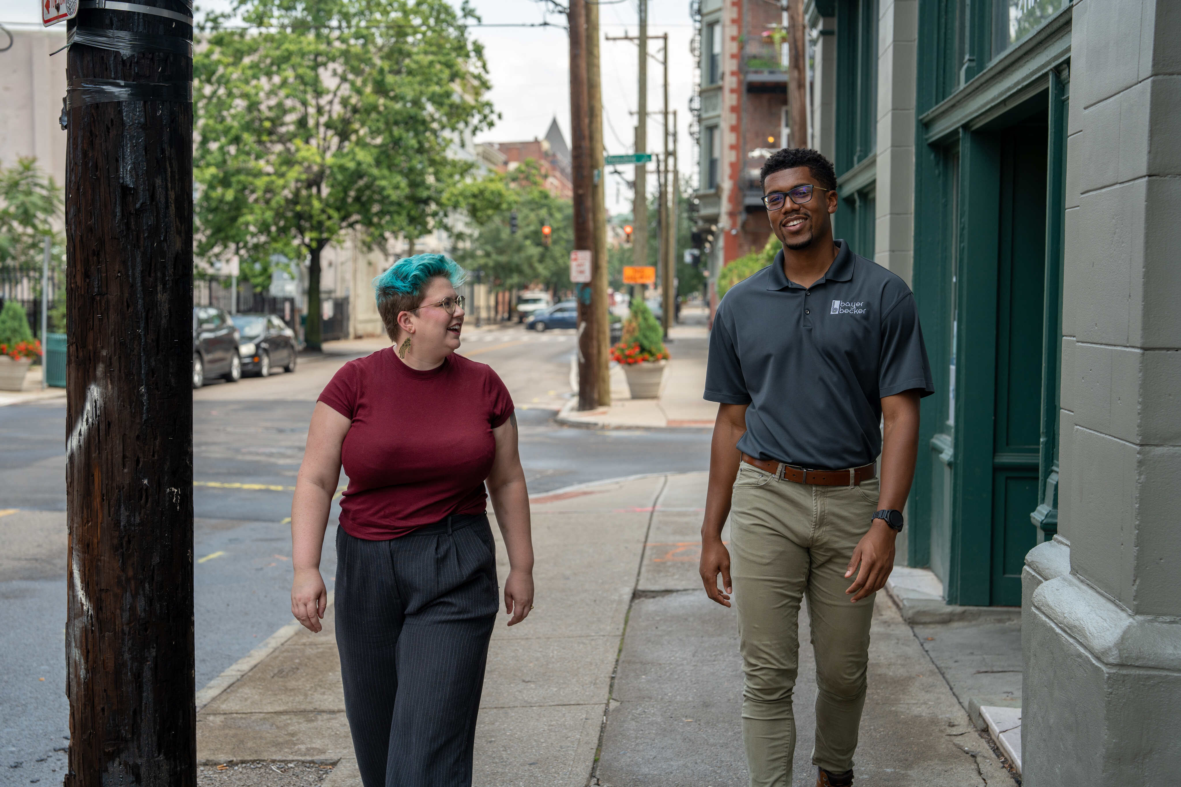 Two people walking on a sidewalk, smiling and talking.