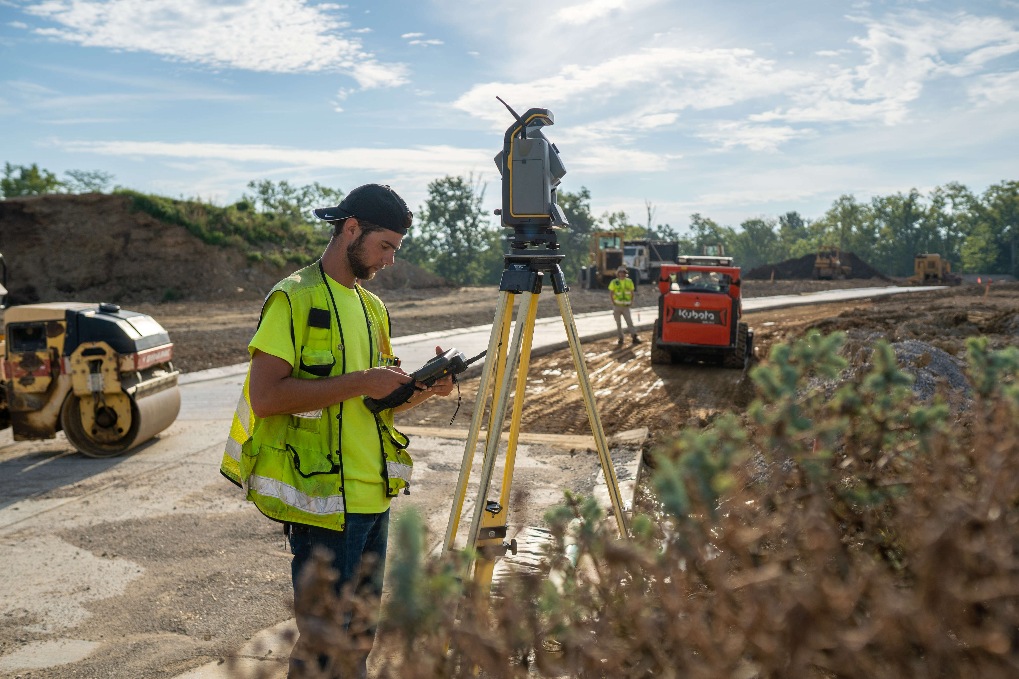 Construction worker using surveying equipment outdoors.