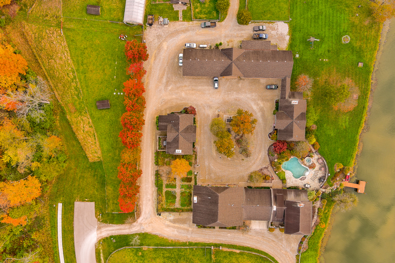 Aerial view of a large house complex with autumn trees and a nearby pond.