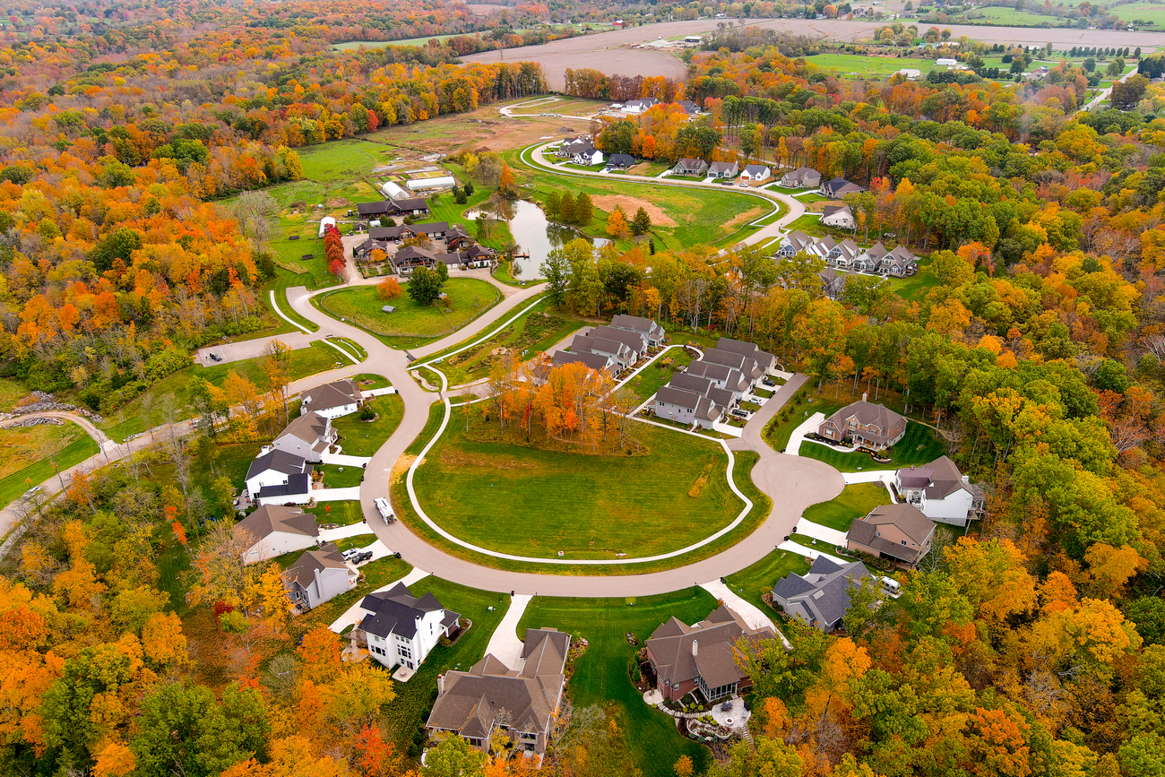Aerial view of a suburban neighborhood with fall foliage surrounding curved streets.