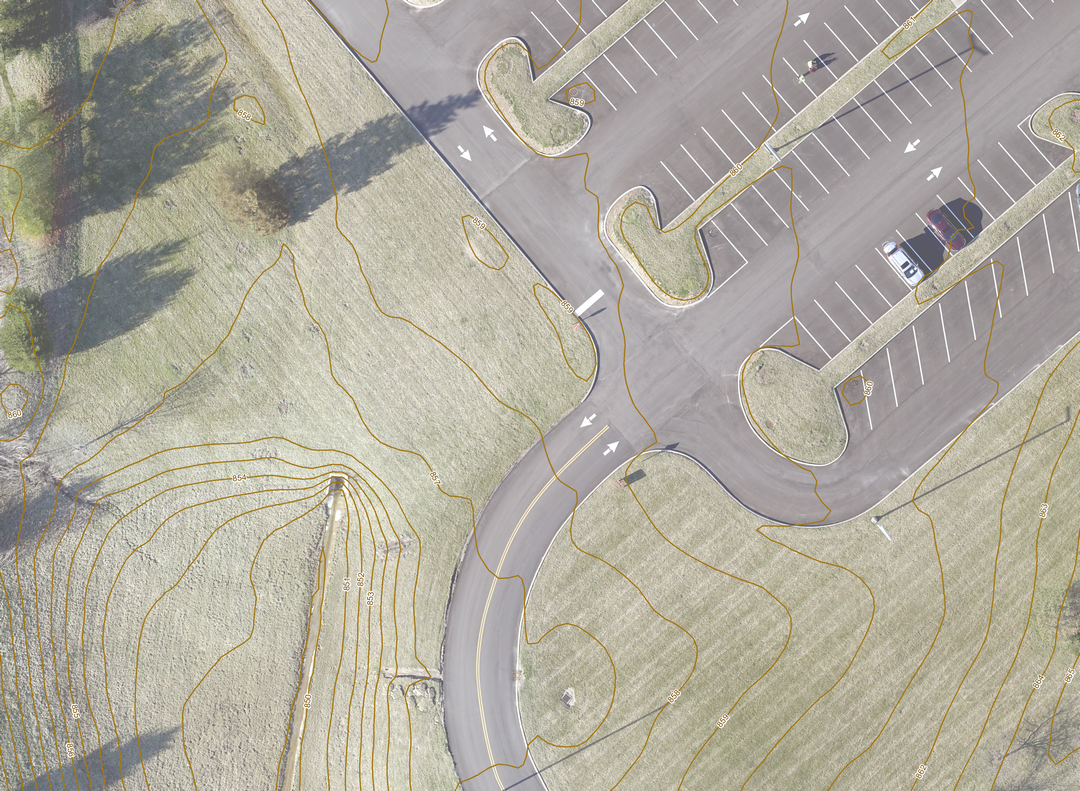 Aerial view of a parking lot and green fields with contour lines.