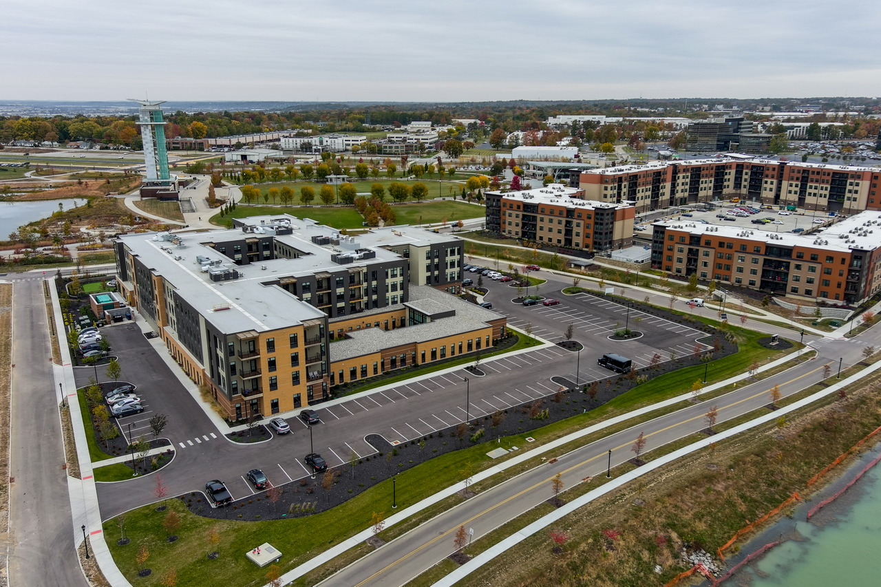 Aerial view of modern apartment complex with parking lots and green spaces.