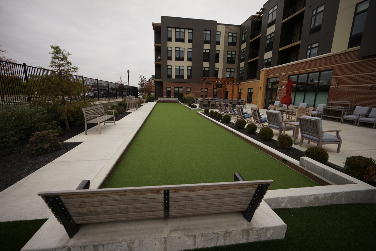 Outdoor seating area by a bocce court near a modern apartment building.