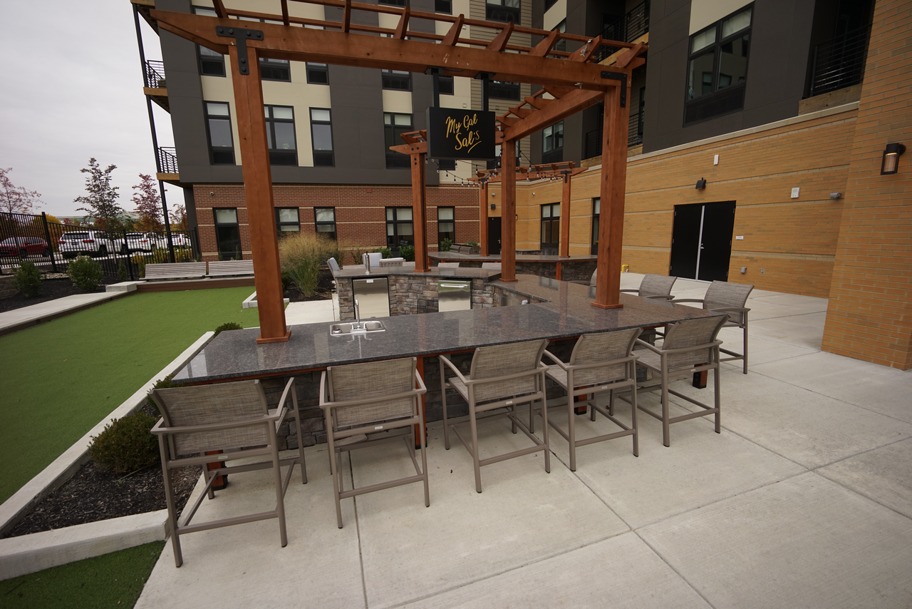 Outdoor dining area with a long table, chairs, and a pergola.