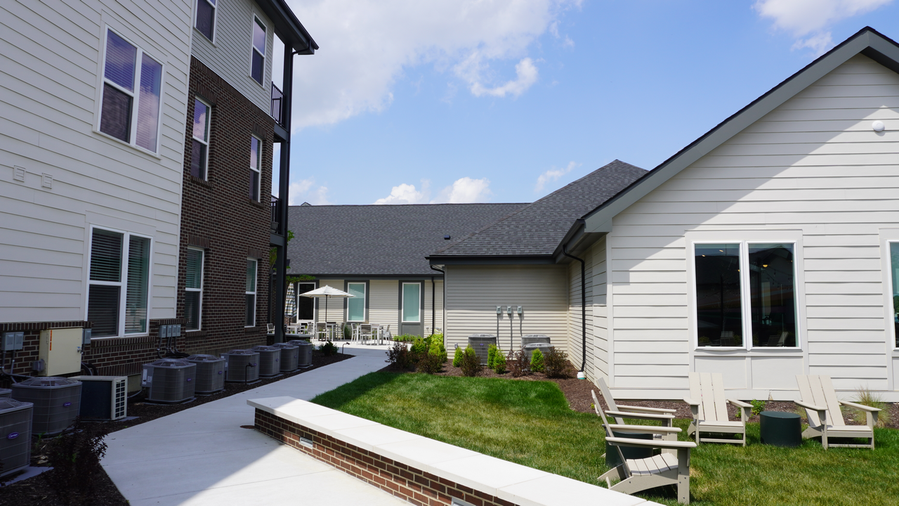 Courtyard with grass, white and brown buildings, and blue sky.