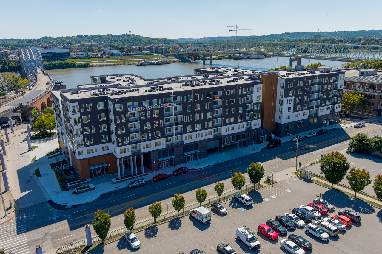 Modern apartment building near a river, clear sky above.