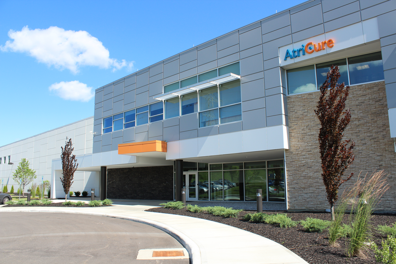Modern building exterior with gray panels, large windows, and a clear blue sky.