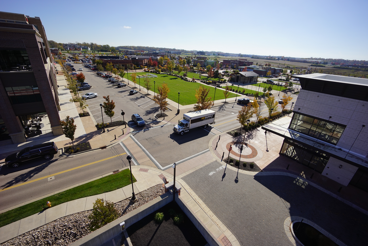Aerial view of an intersection with green park and buildings on a sunny day.