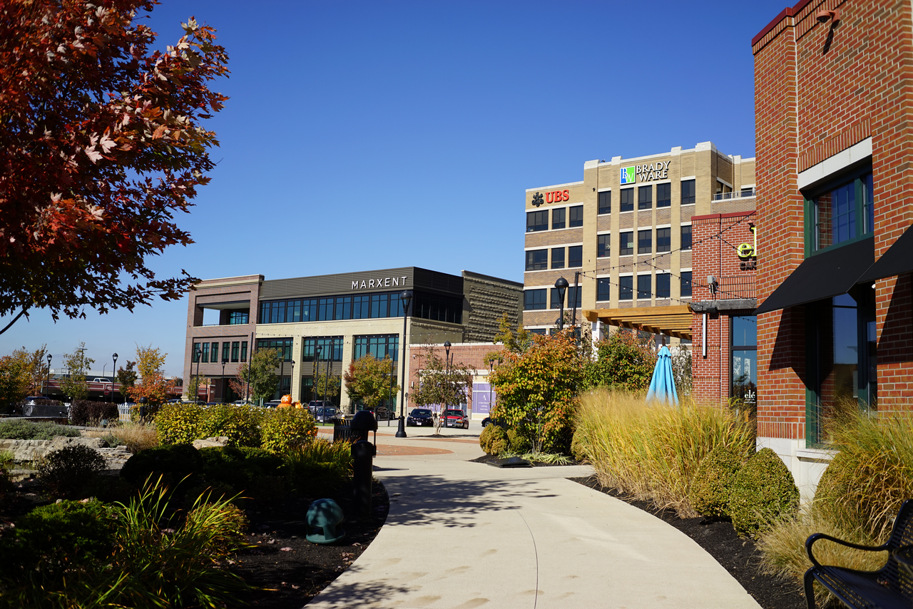 Urban plaza with modern buildings and autumn trees, clear blue sky.