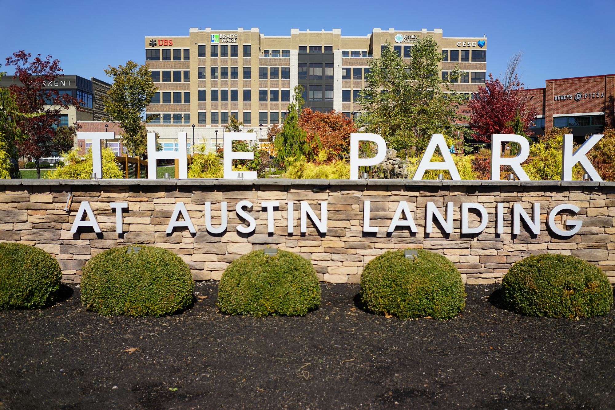 The Park at Austin Landing sign, with buildings and trees in the background.