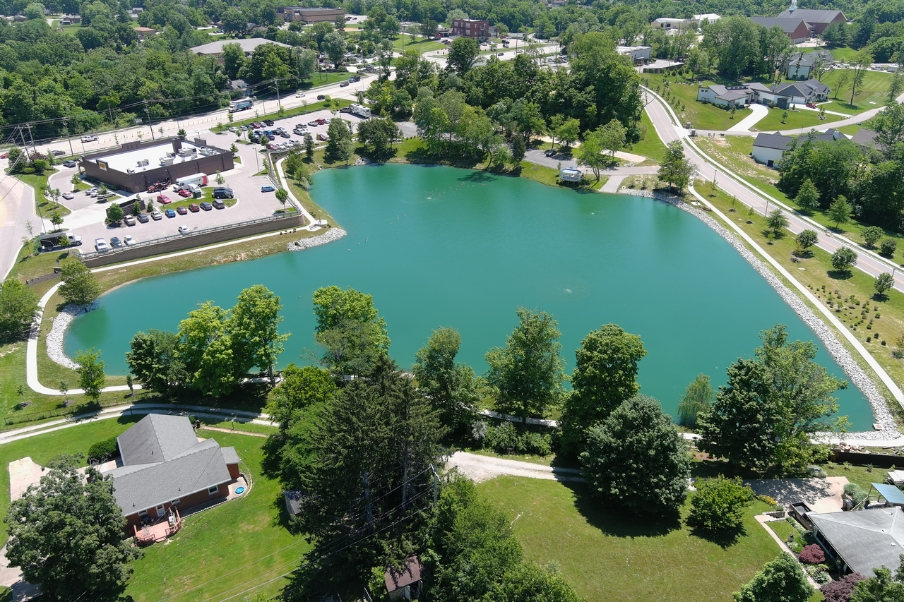 Aerial view of a pond surrounded by trees and buildings.