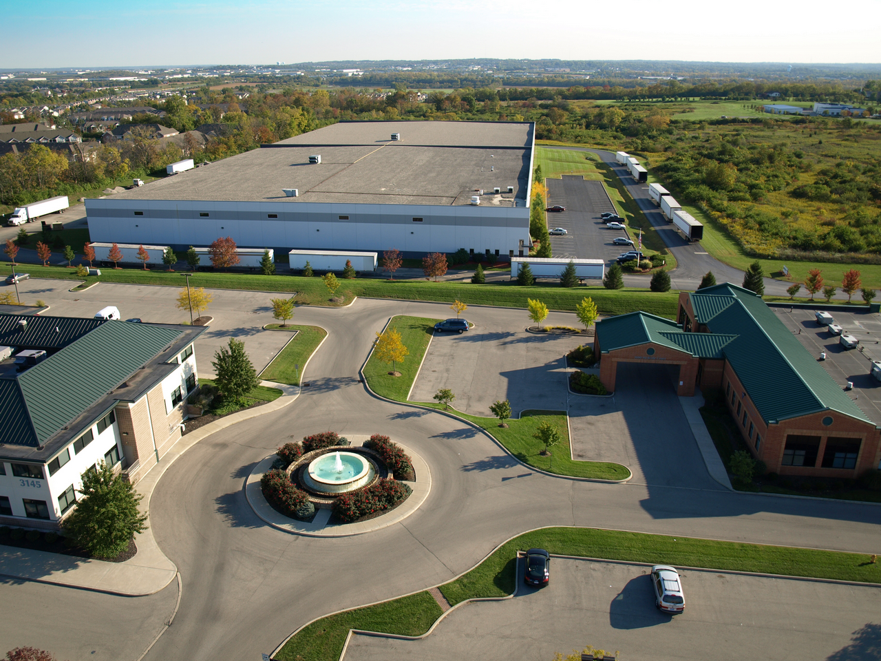 Aerial view of office buildings, parking lots, and a fountain on a clear day.