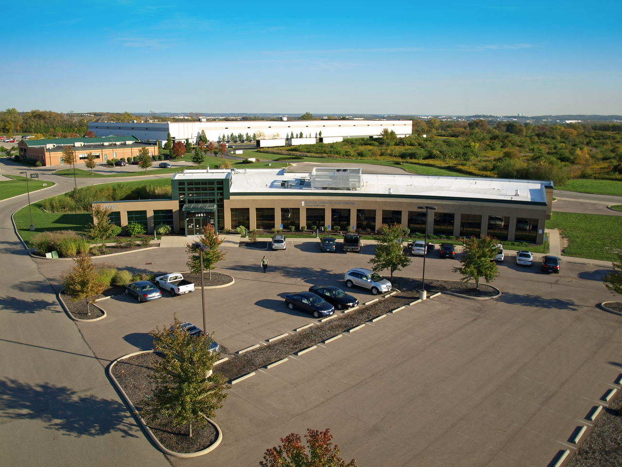 Aerial view of a small office building with a parking lot and trees.