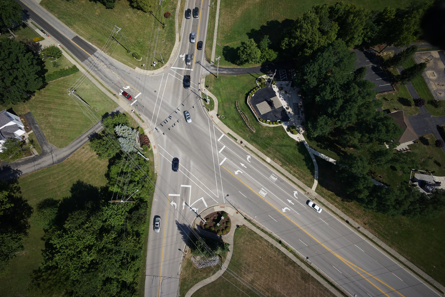Aerial view of a multi-lane road intersection with traffic and greenery.