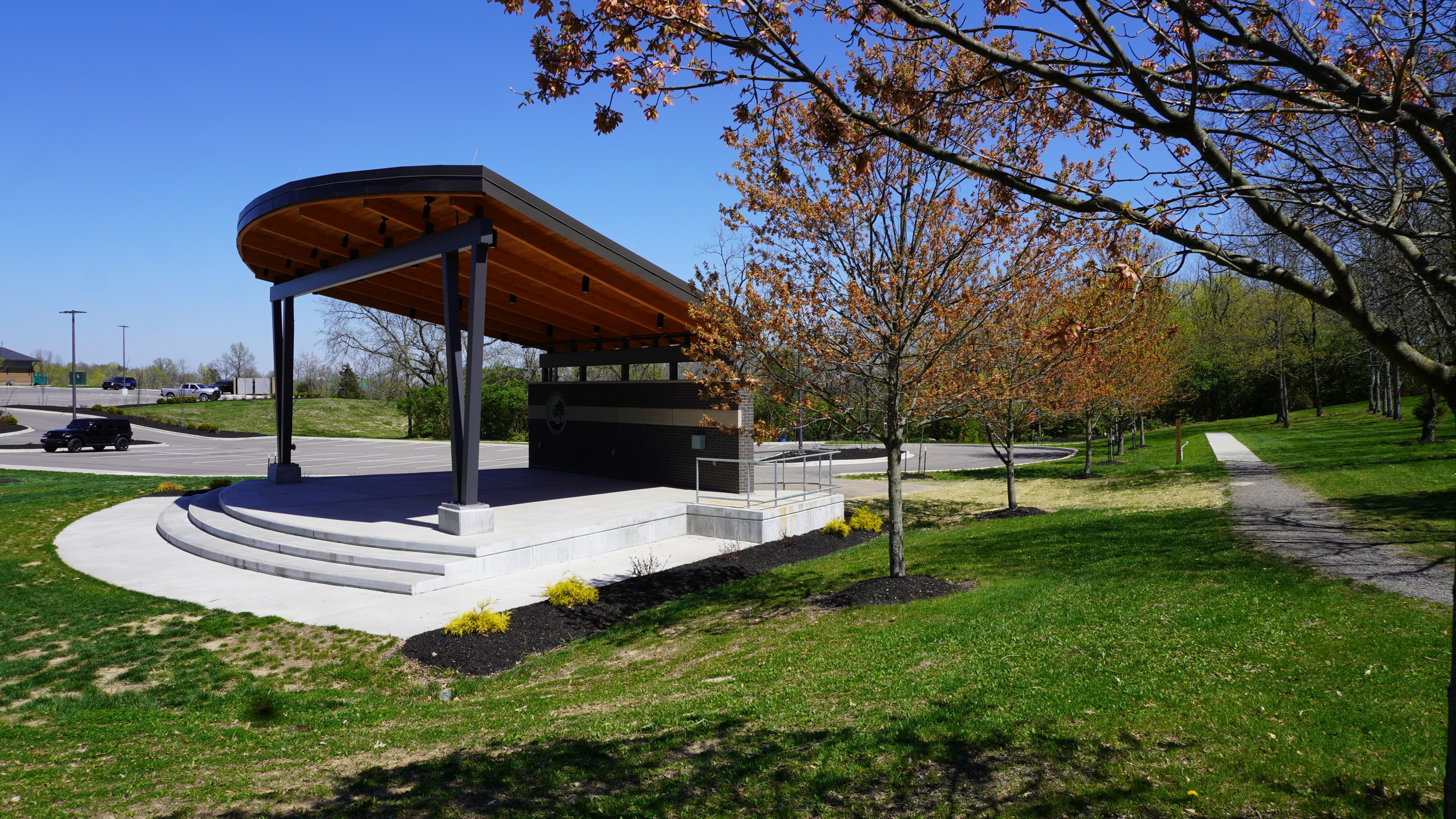 Outdoor amphitheater with trees and bright blue sky.