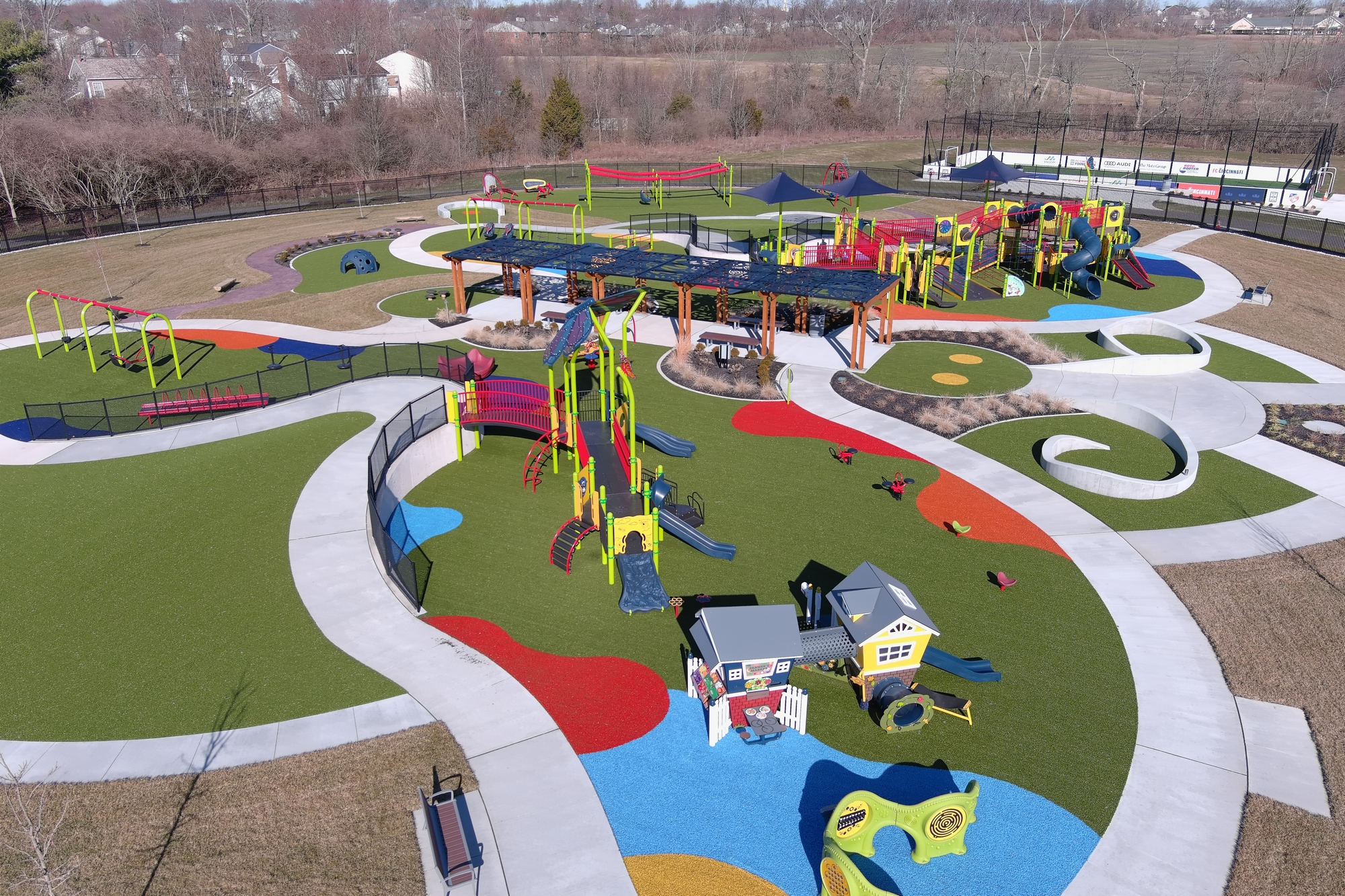 Colorful playground with slides and climbing structures on green and red surfaces.