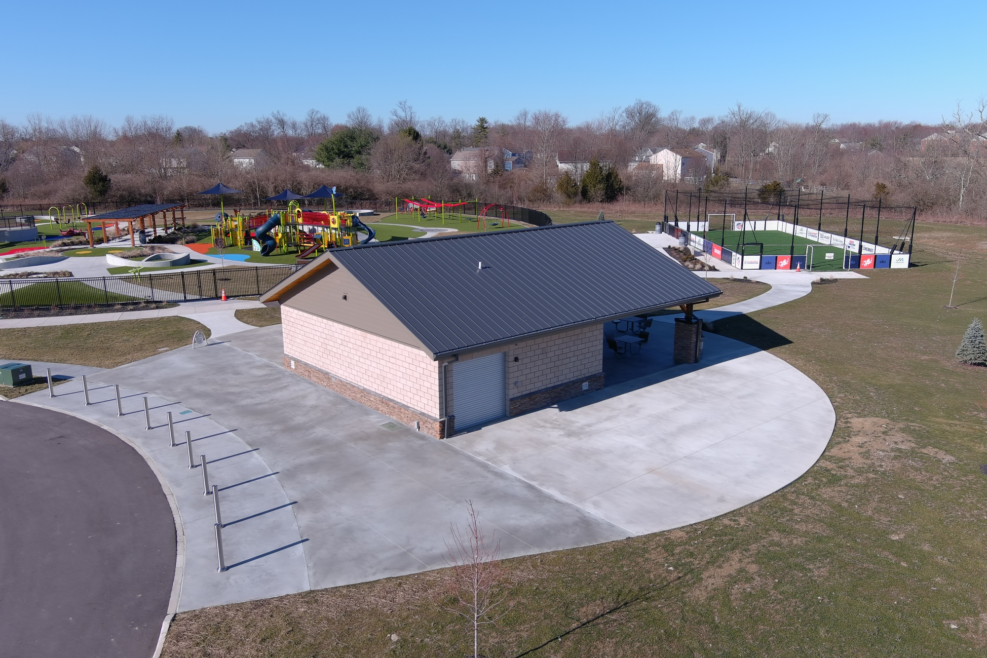 Park with a building, playground, and sports field on a clear day.