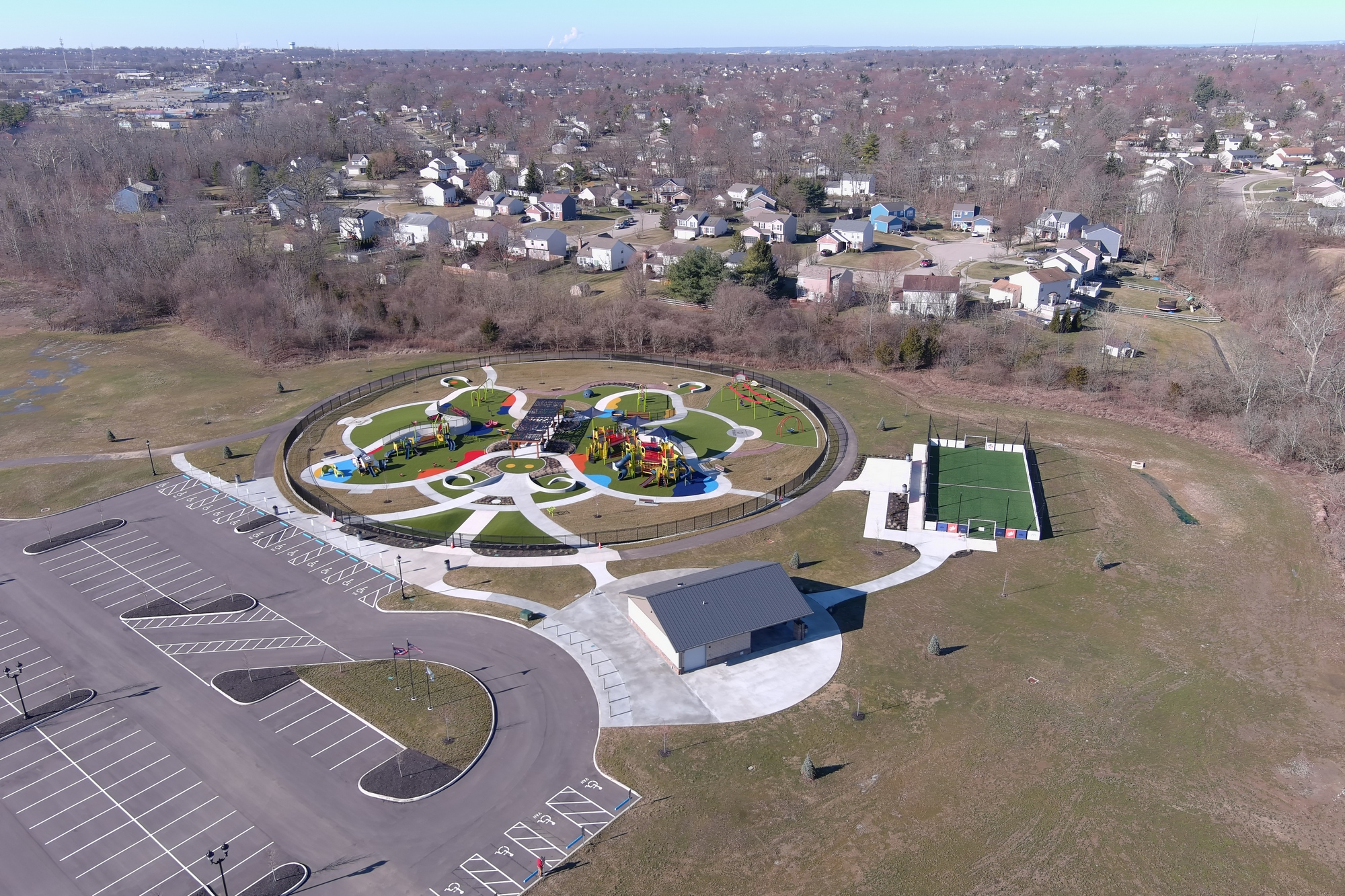 Aerial view of a colorful park with play areas, surrounded by residential homes.