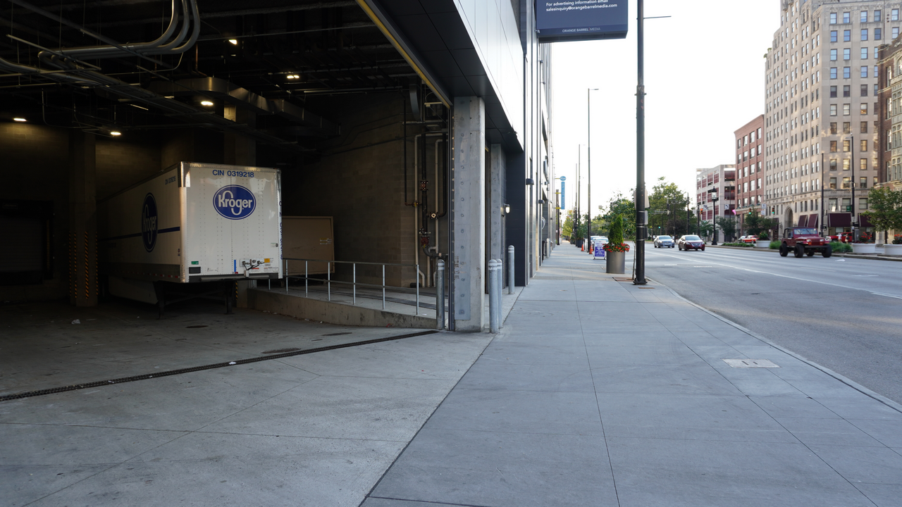 Truck parked at loading dock, city street view, afternoon light.