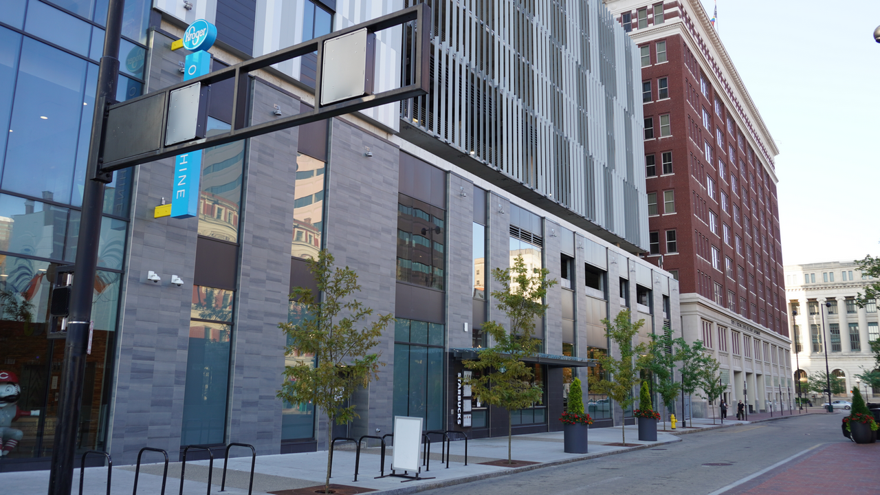 Modern buildings along a city street with trees and clear skies.