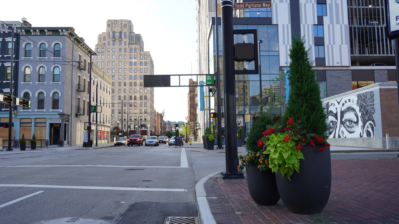 Urban street with large planters and tall buildings in the background.