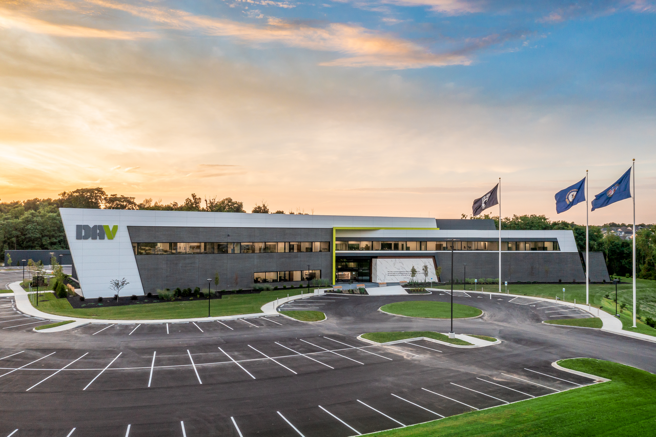 Modern office building with flags and empty parking lot at sunset.