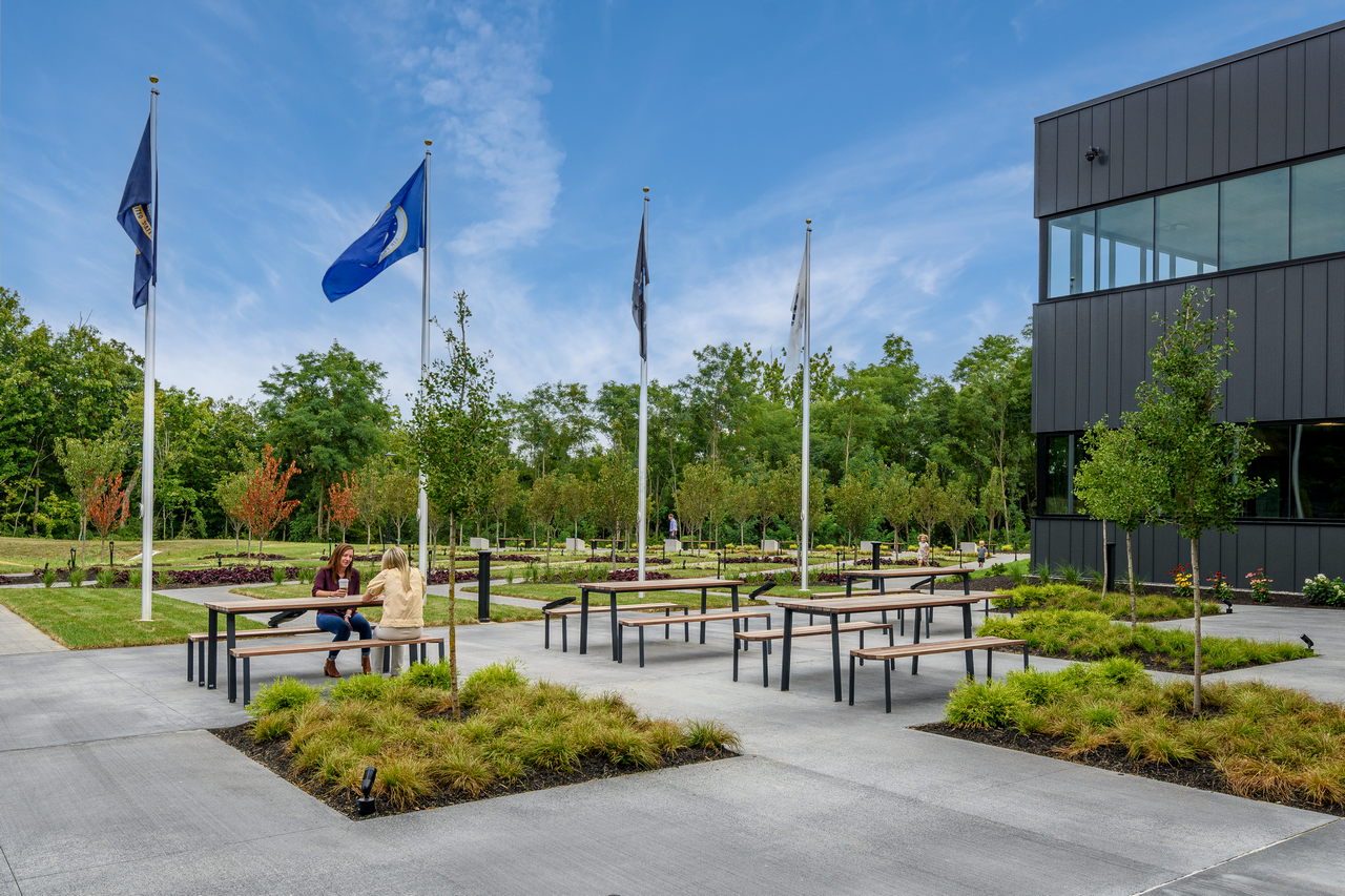 Outdoor seating area with flags and modern building.
