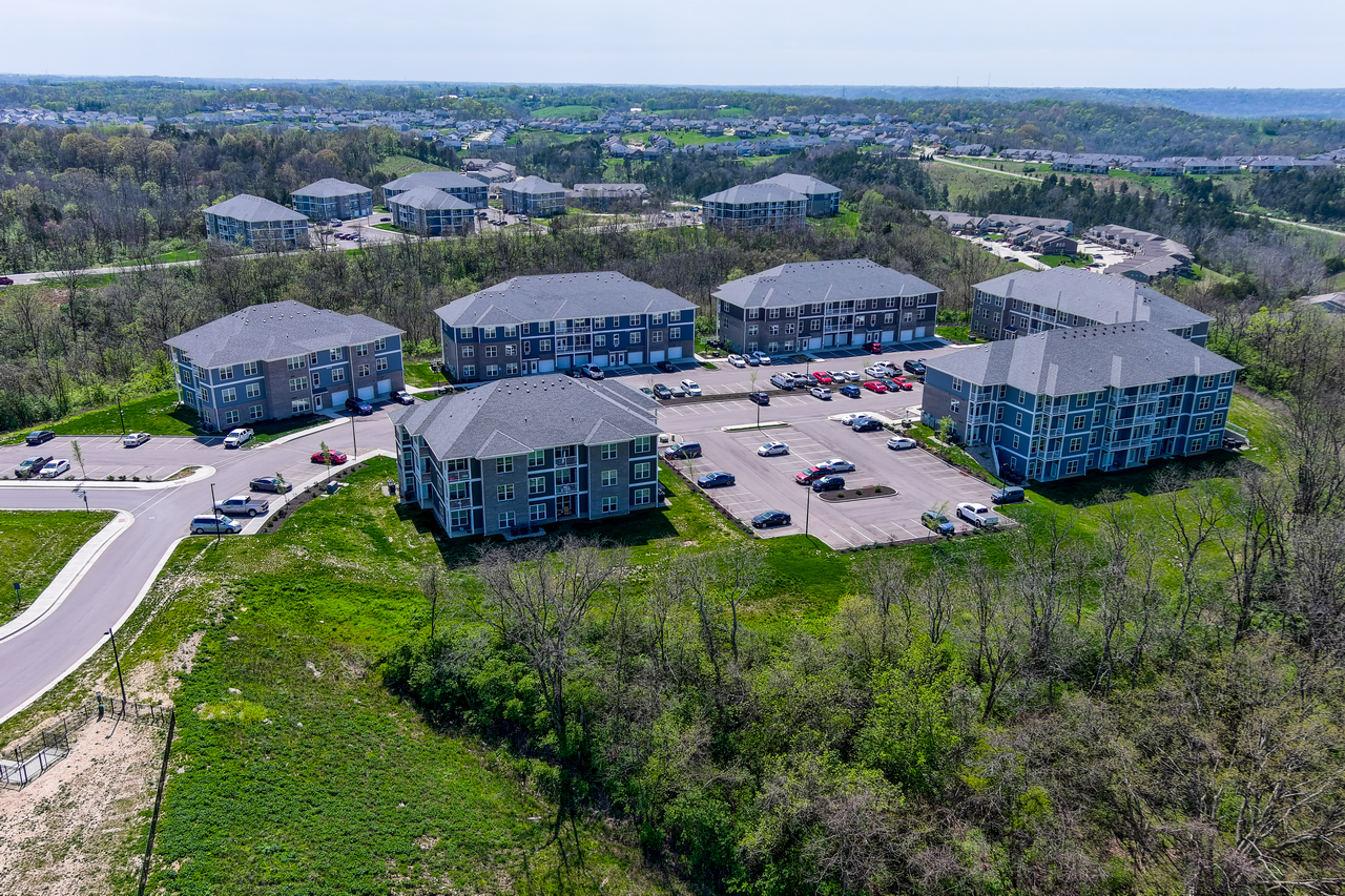 Aerial view of apartment complex surrounded by greenery and roads.