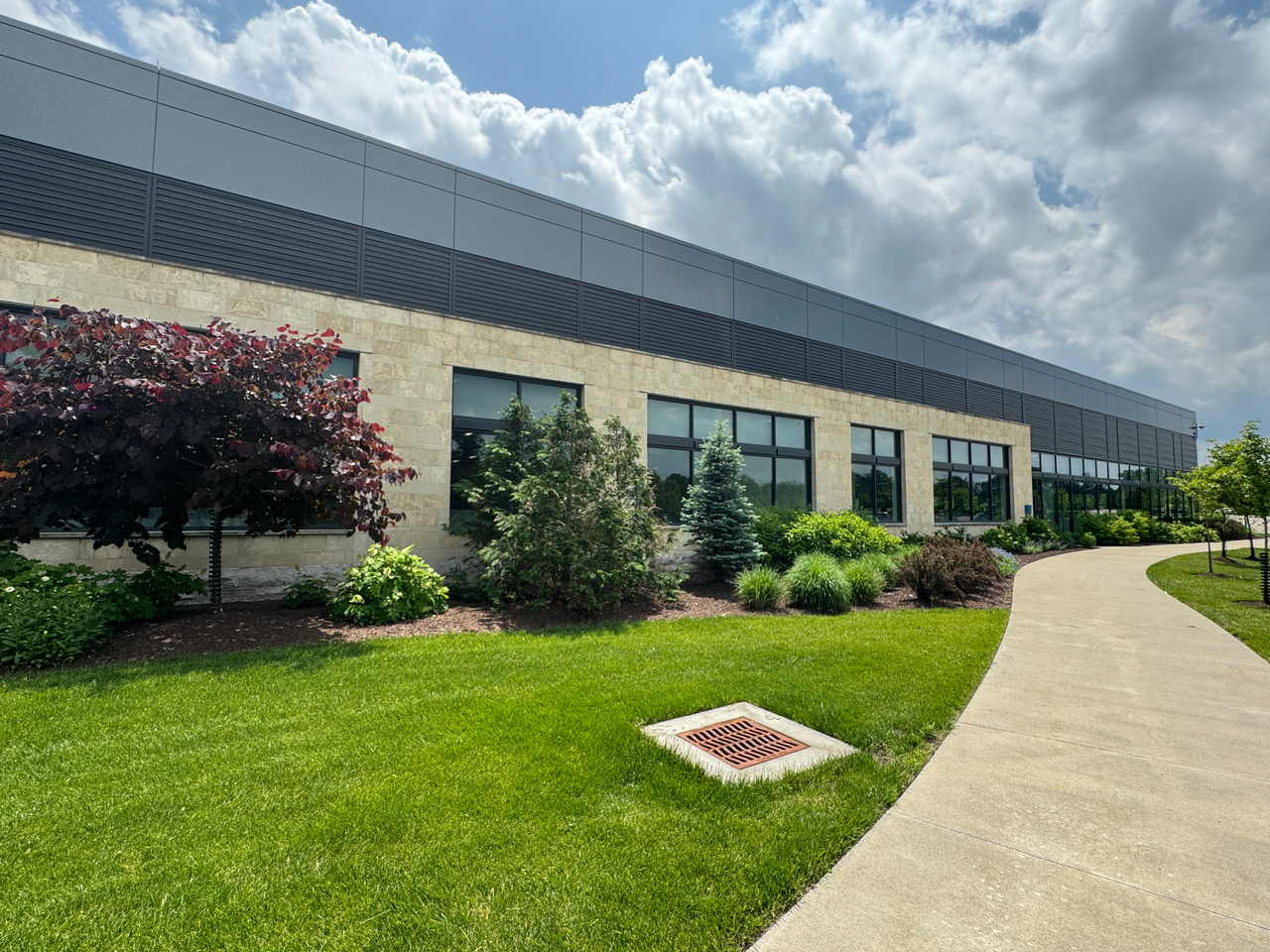 Modern building with landscaped greenery and a clear sky.
