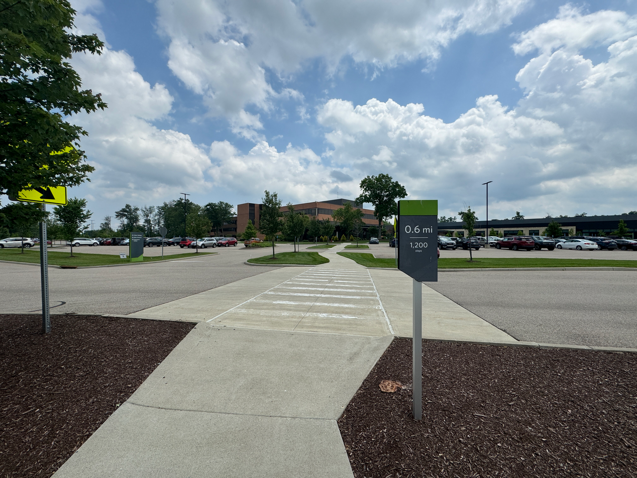 Pathway leading to a building under a cloudy sky in a parking lot.