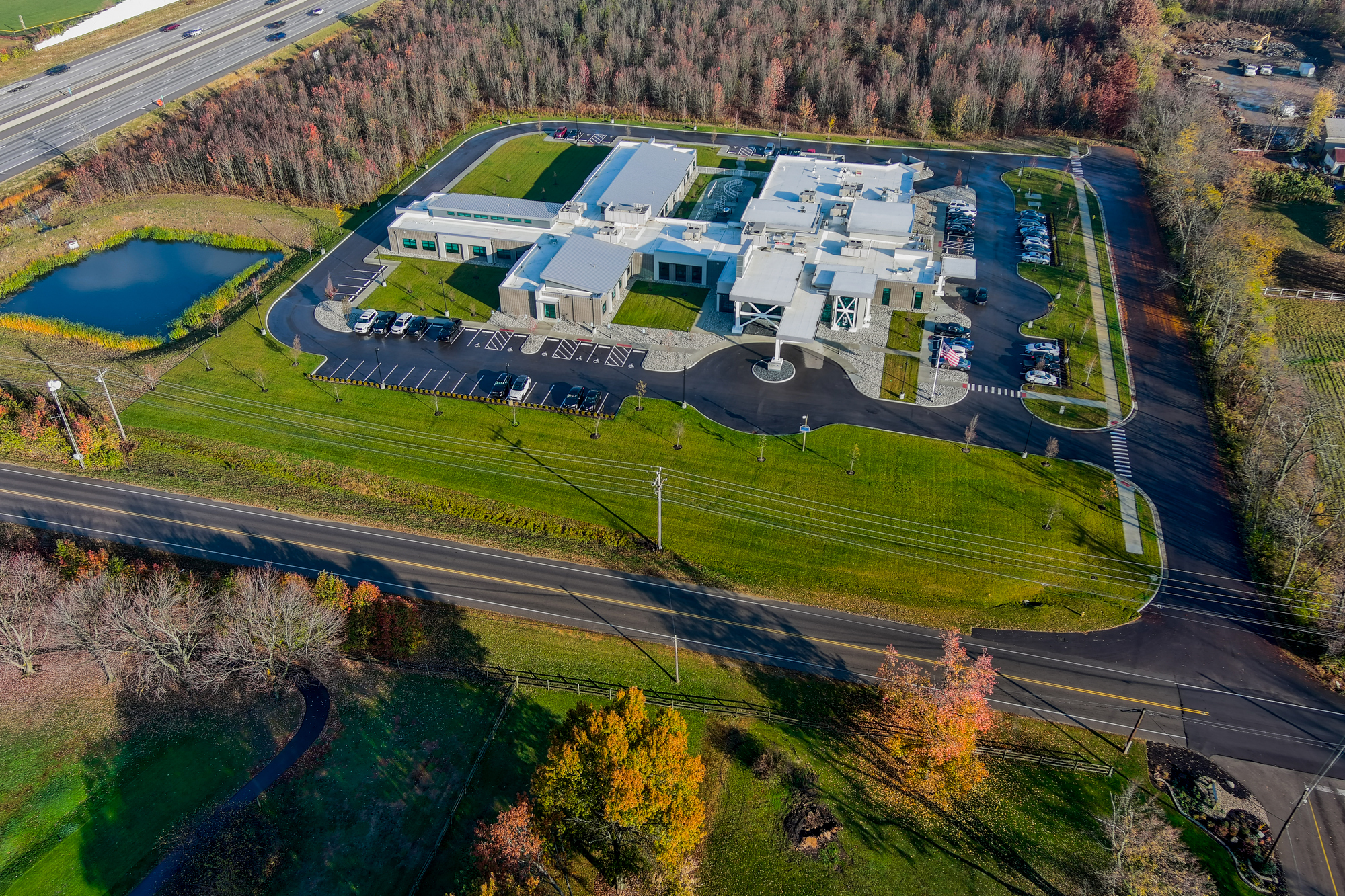 Aerial view of a large building with parking, surrounded by green grass and trees.