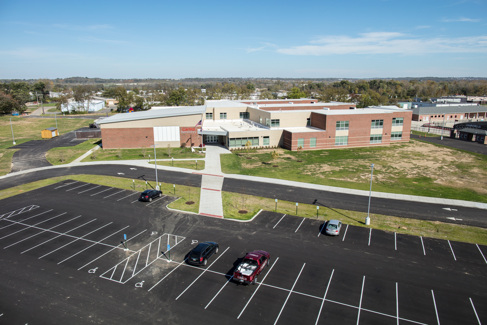 School building with large parking lot on a sunny day.