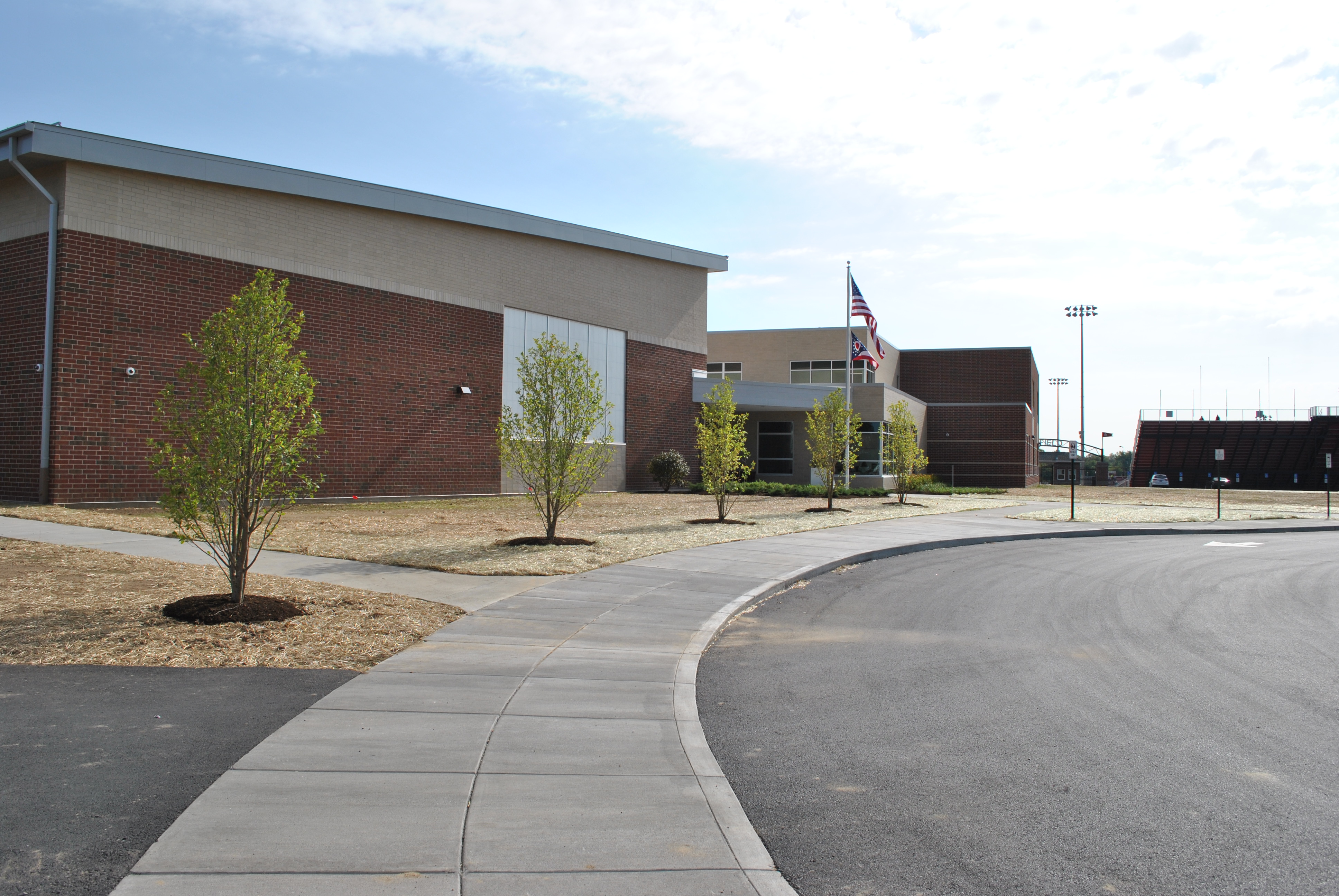 School building with red bricks, small trees, and a curved pathway.