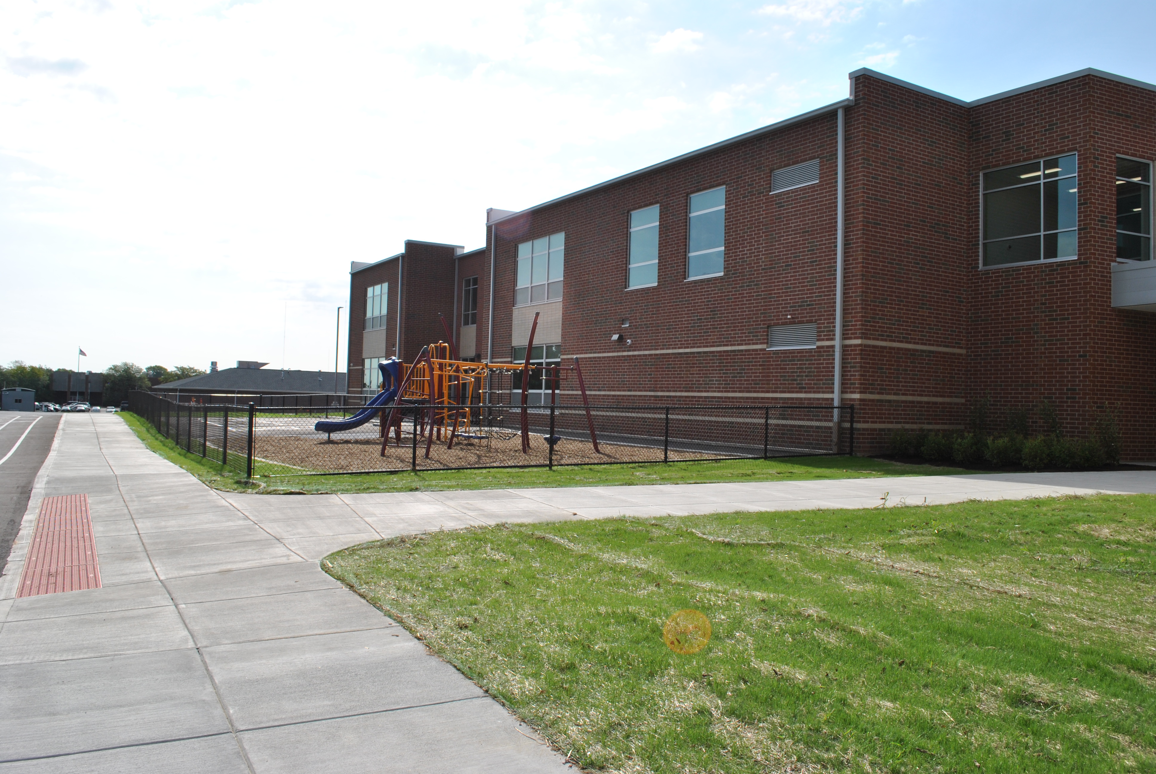 Red brick school building with adjacent playground and slide.