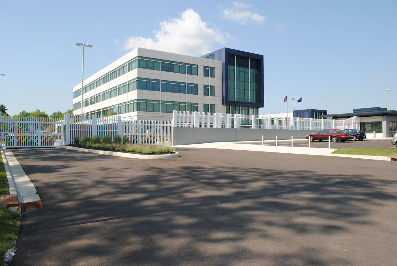 Modern office building with a gated entrance under a clear blue sky.