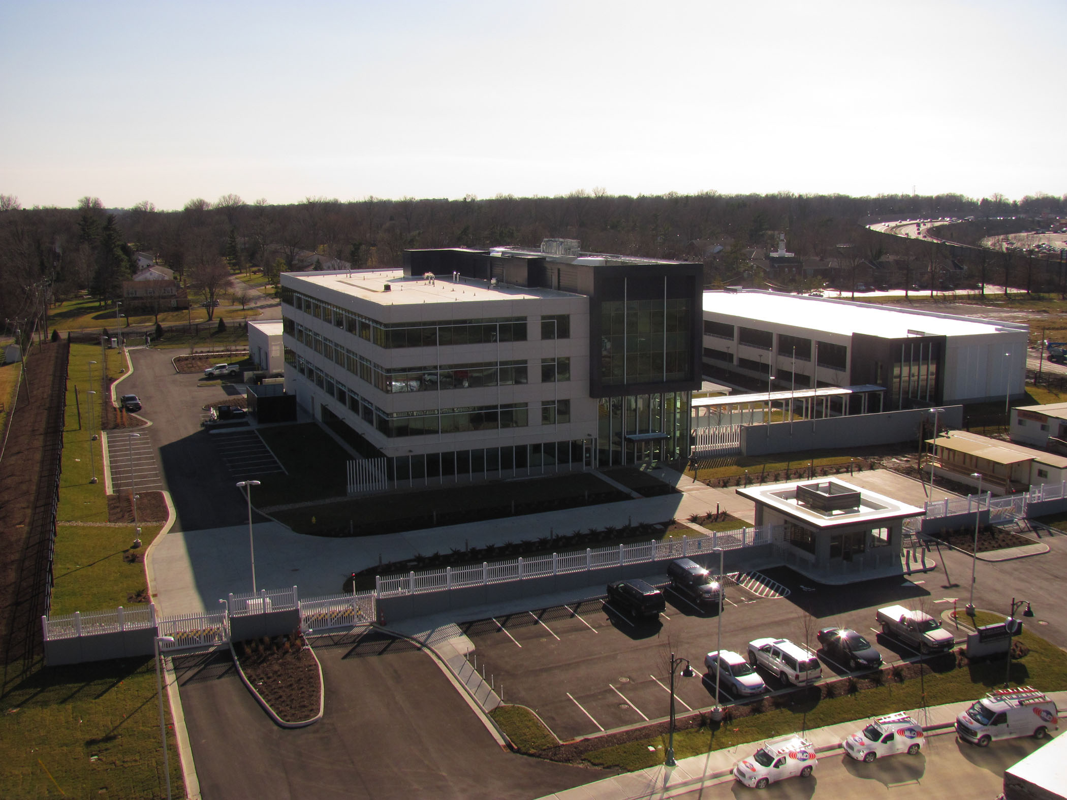 Aerial view of a modern office building with parking lot and surrounding greenery.