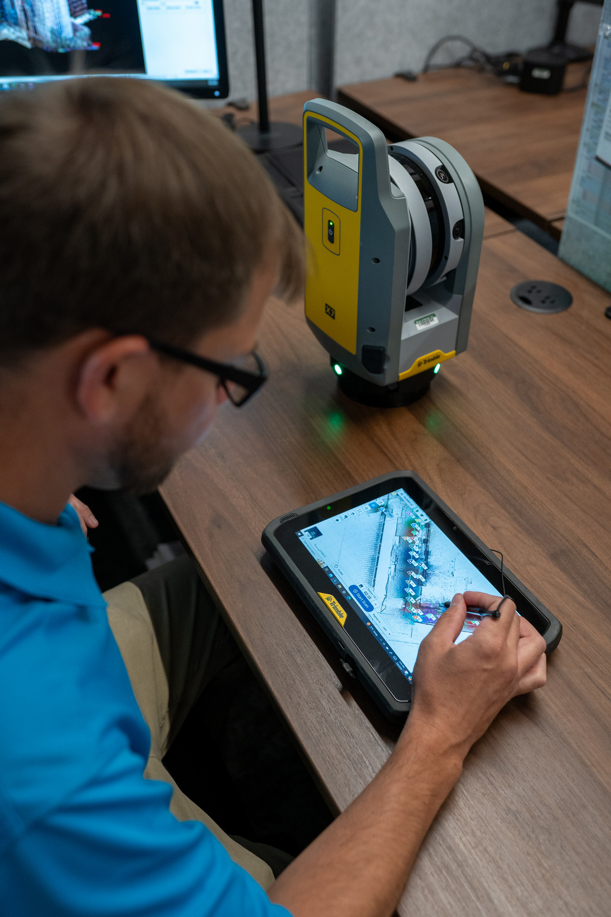 Man using a touchscreen tablet at a desk with electronic equipment.