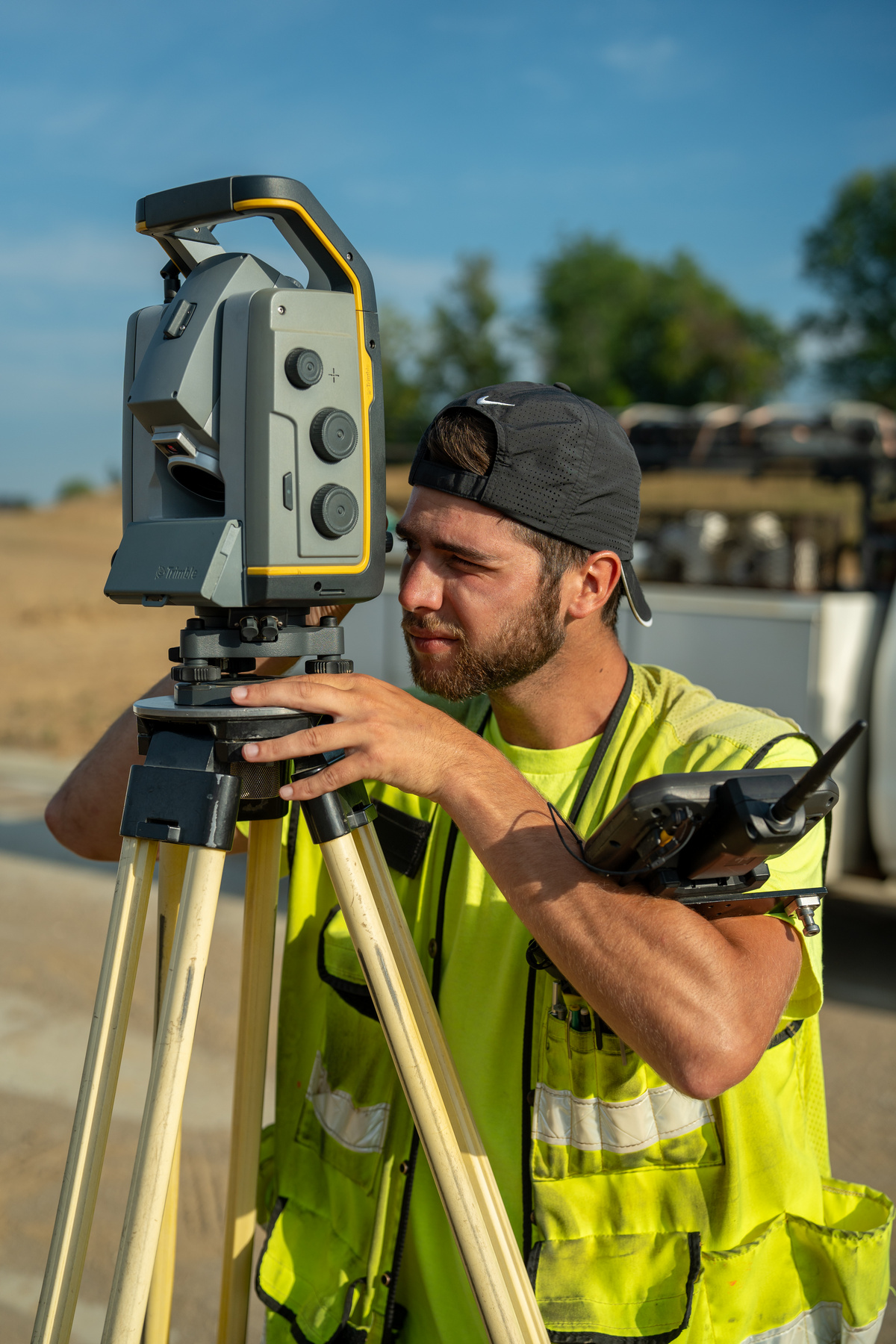 Surveyor using equipment outdoors on a sunny day.