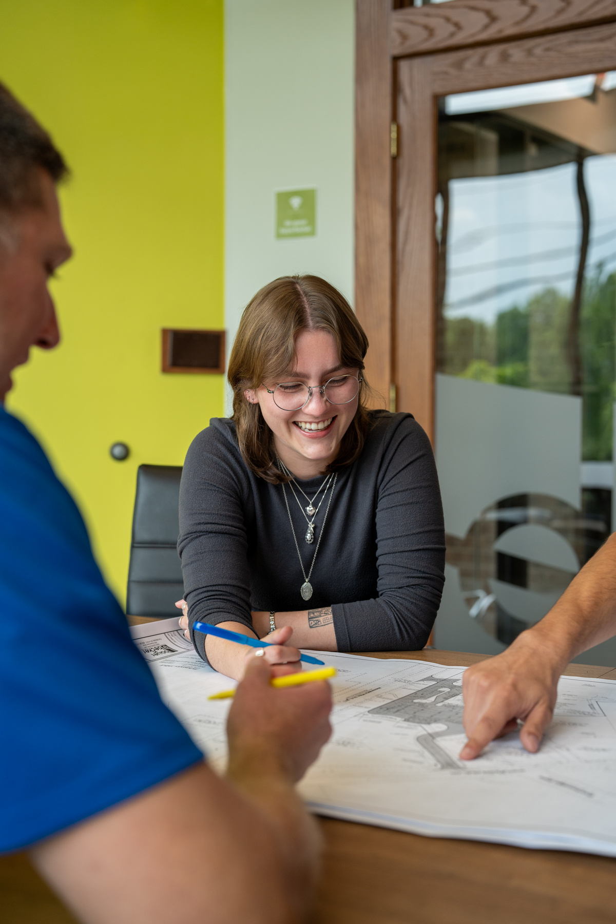 Group discusses plans at table, woman smiling.