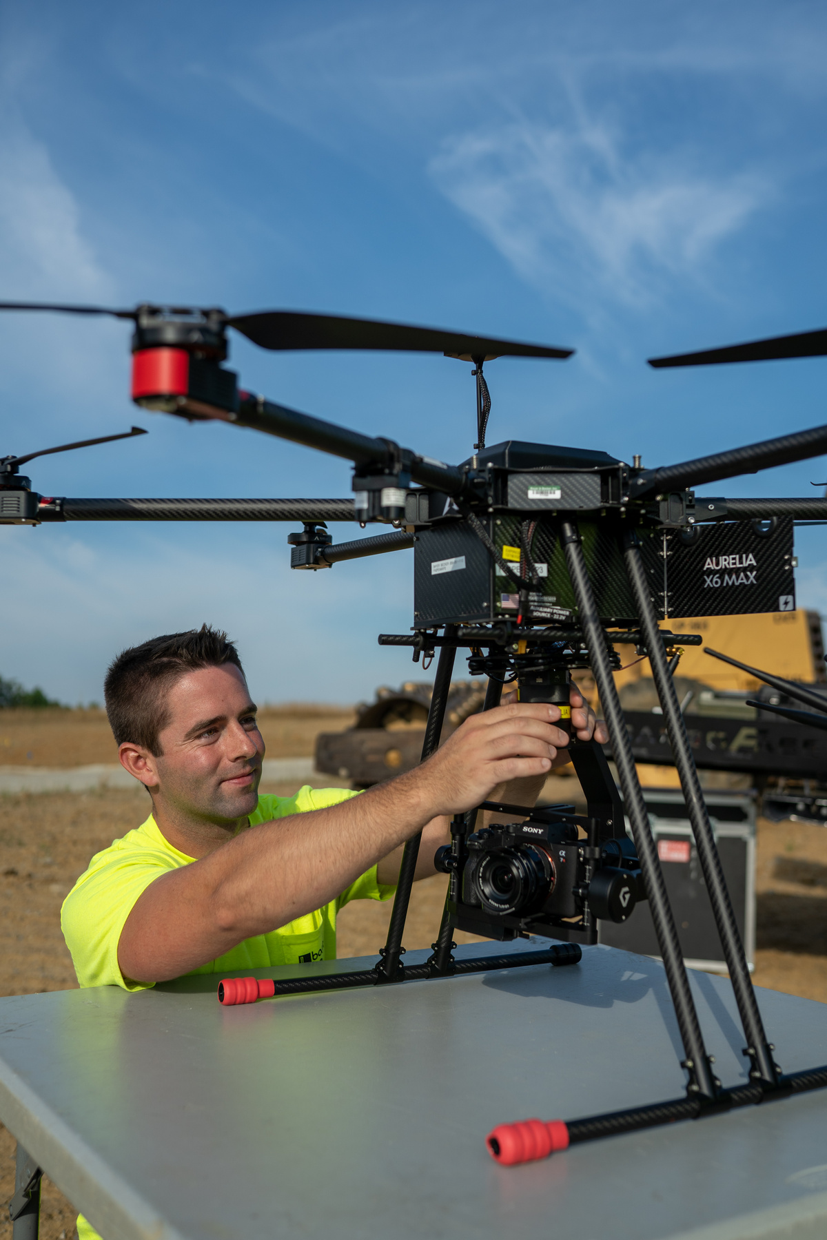 Man adjusting large drone outdoors on a sunny day.