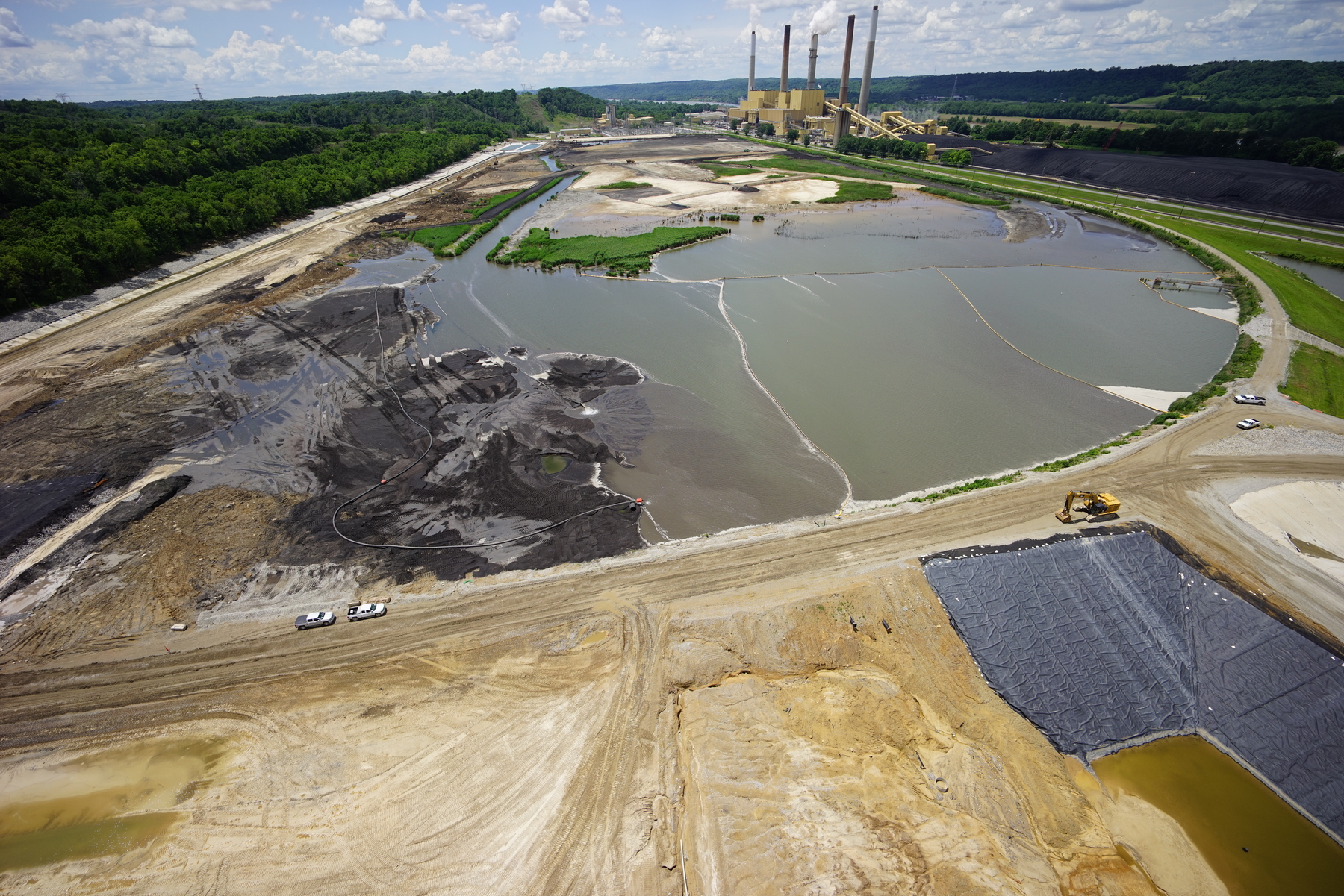 Aerial view of industrial site with large ponds and a power plant in the background.