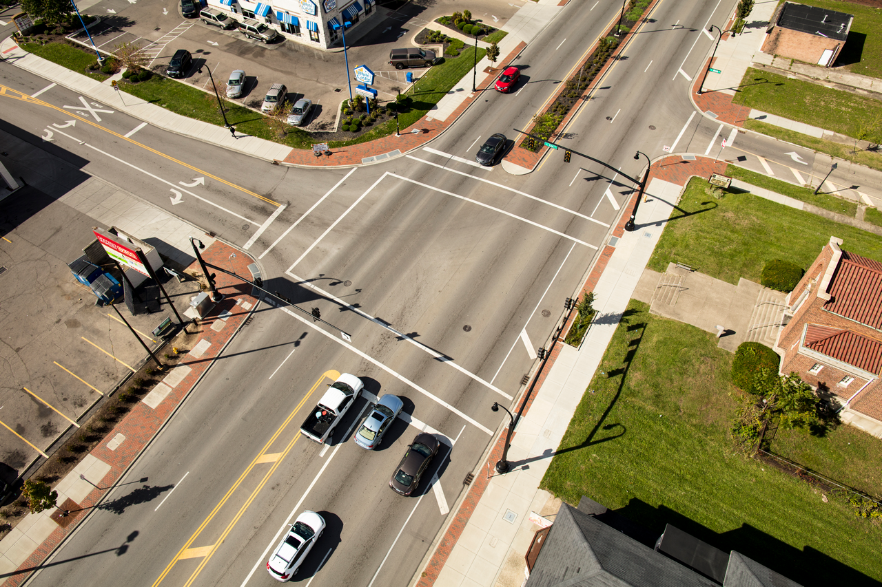 Cars at a sunny intersection, aerial view.