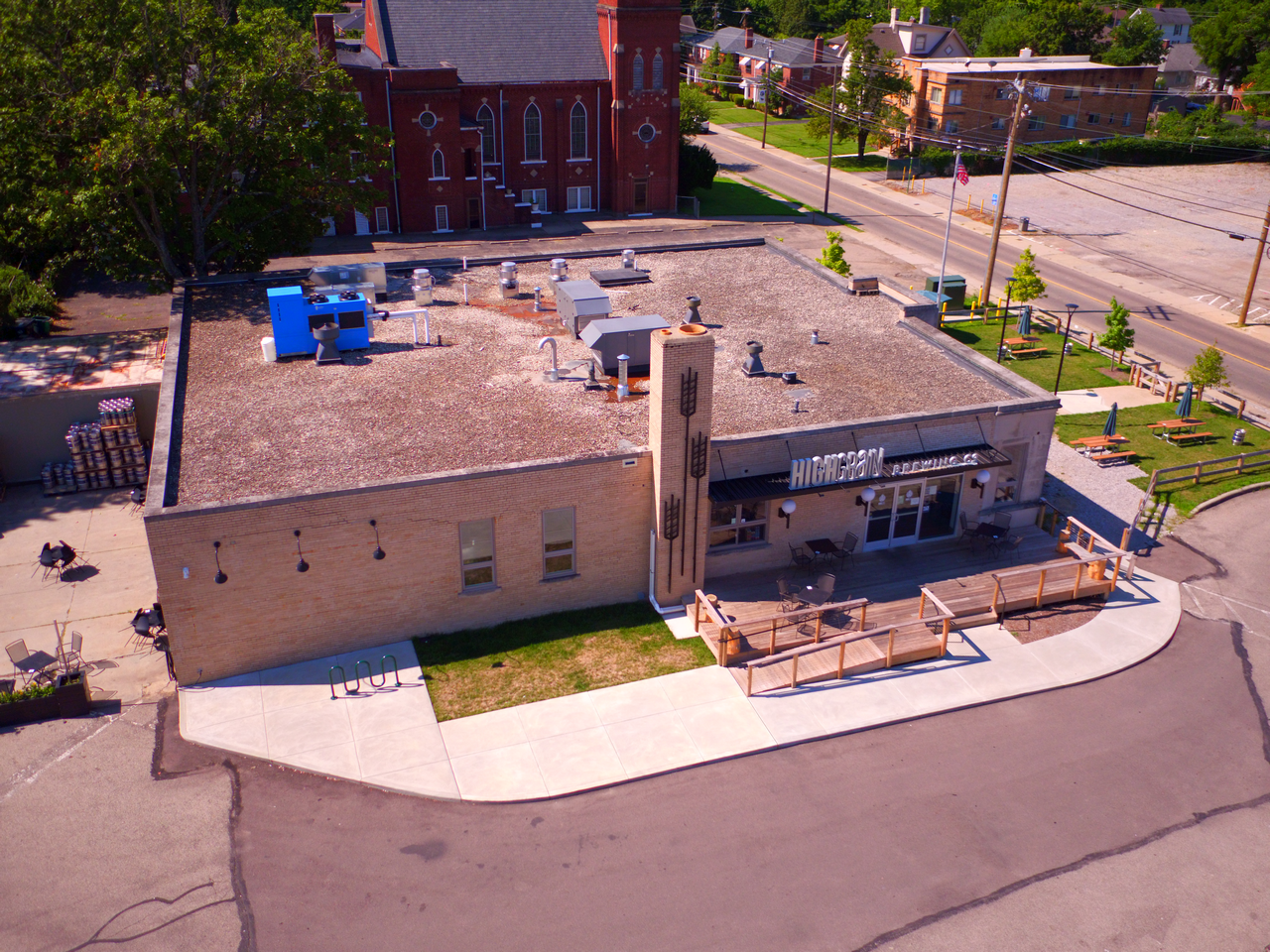 Brick building on a corner lot with rooftop equipment and surrounding greenery.