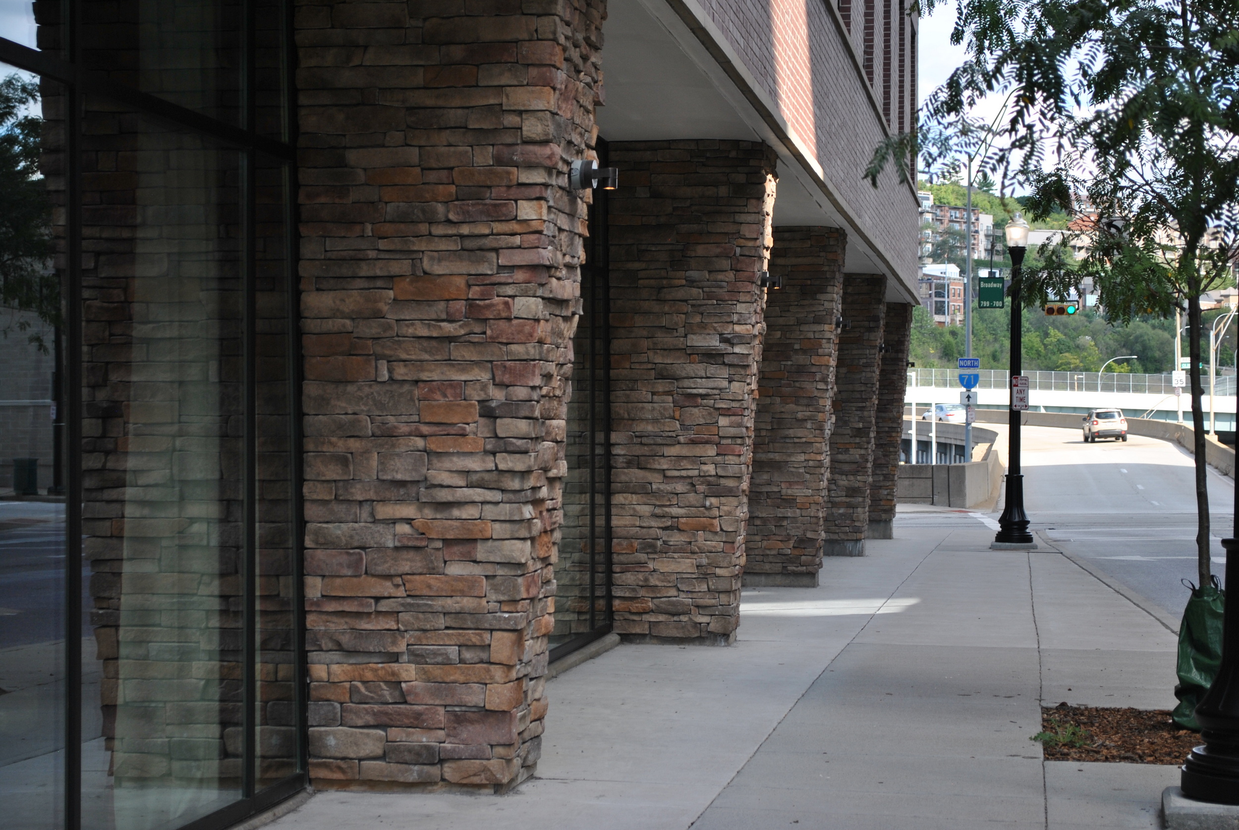 Stone columns line a sidewalk near a modern building.