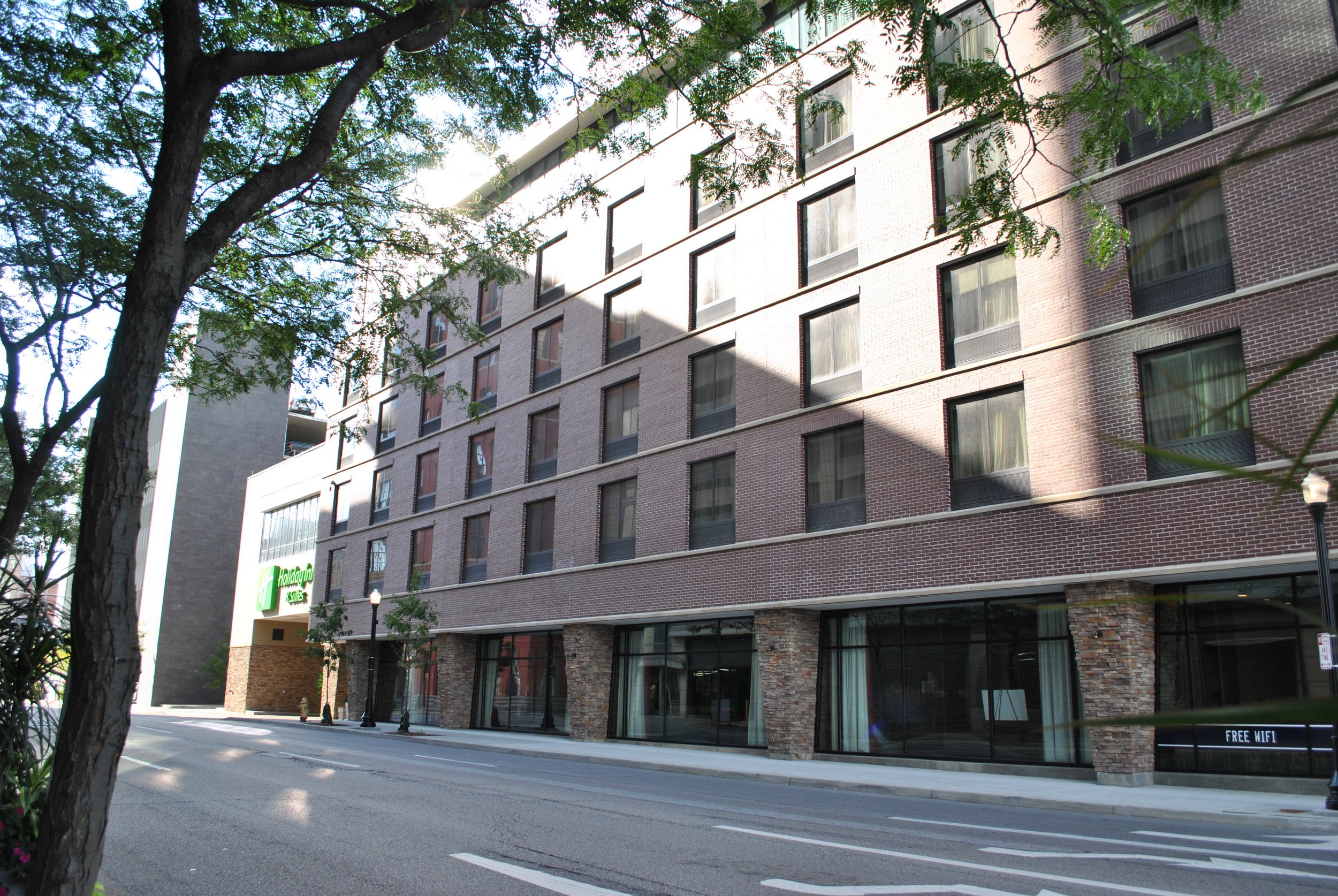 Street view of a five-story brick building with large windows.