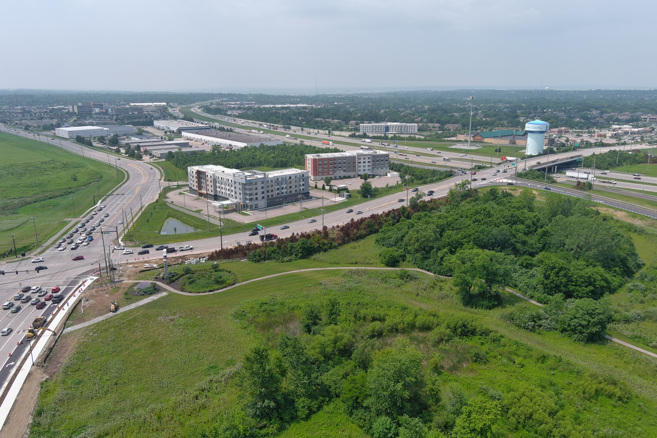 Aerial view of highway, buildings, and green landscape.