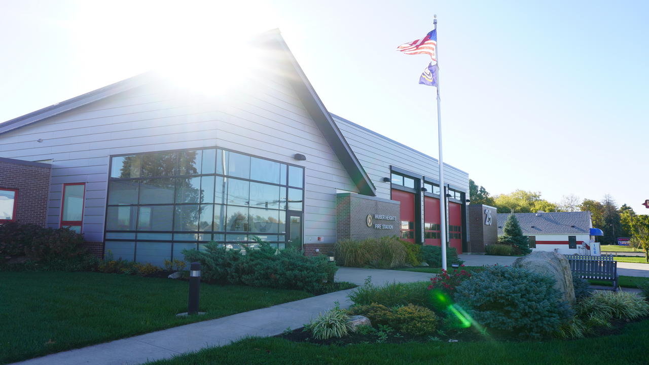Sunlit building with two flags and landscaped garden.