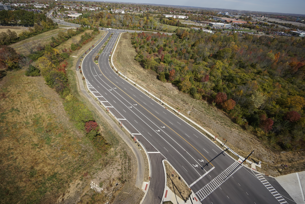 Curved highway through wooded landscape, autumn colors visible.