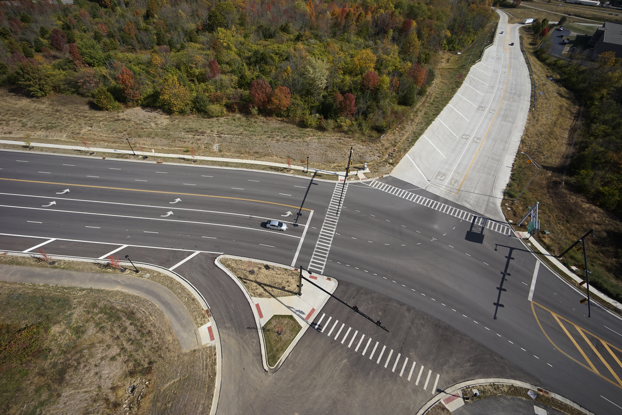 Aerial view of an empty road intersection bordered by autumn trees.