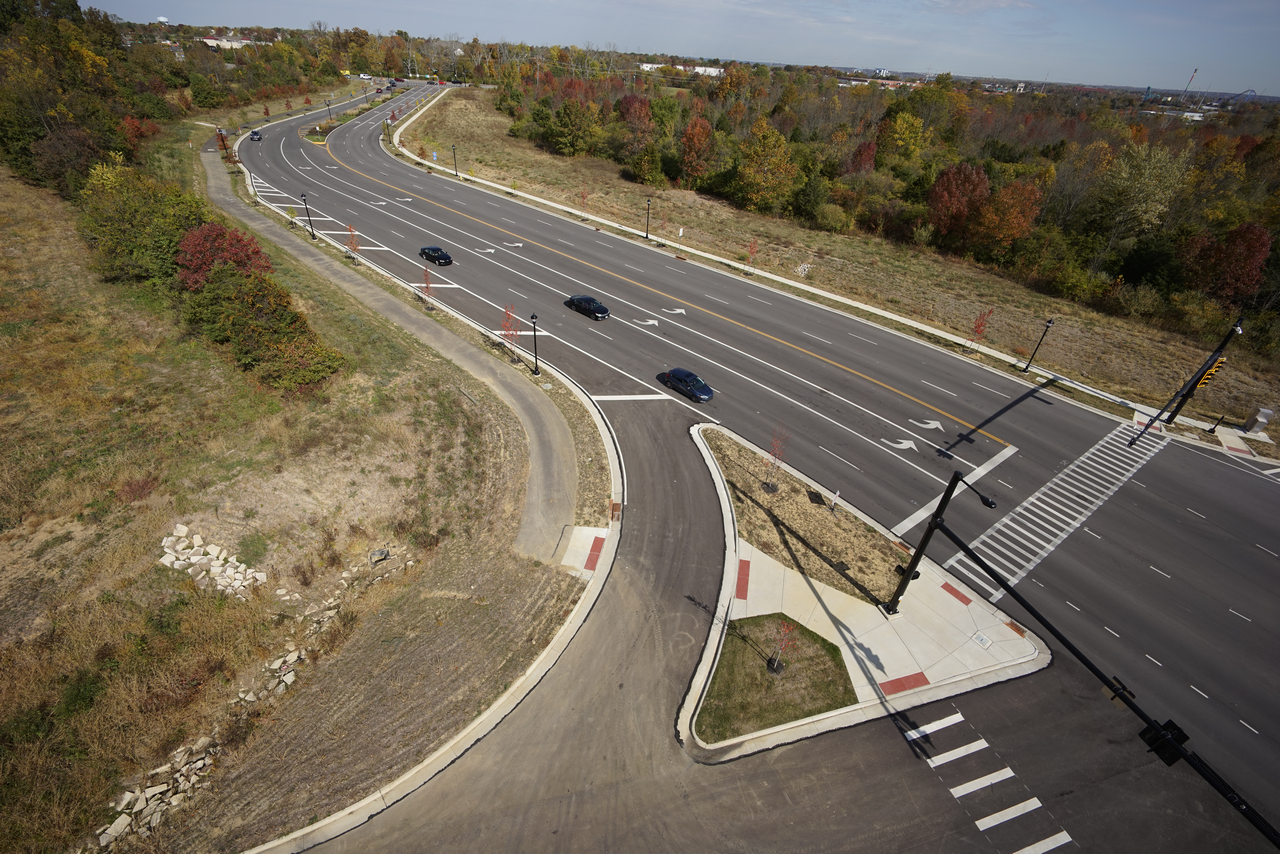 Curved road intersection with sparse cars, surrounded by autumn trees.